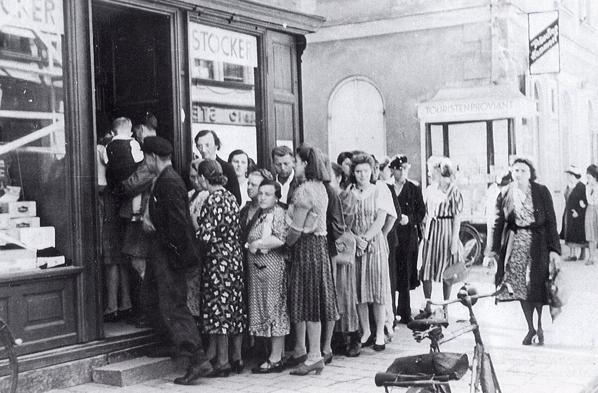 Die Schlange vor dem Tabakladen von Franz Stocker in der Münchener Straße 7 paßte nicht ins offiziell verordnete Bild. Der Film mit dieser und 14 ähnlichen Aufnahmen wurde dem pensionierten Reichsbankrat Ernst Seiffert am 26.7.1941 von der Polizei abgenommen.